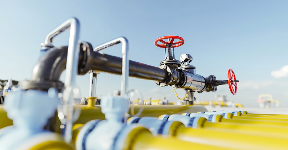 Close-up of black pipe with red valves and pressure gauge in an industrial utility setting.