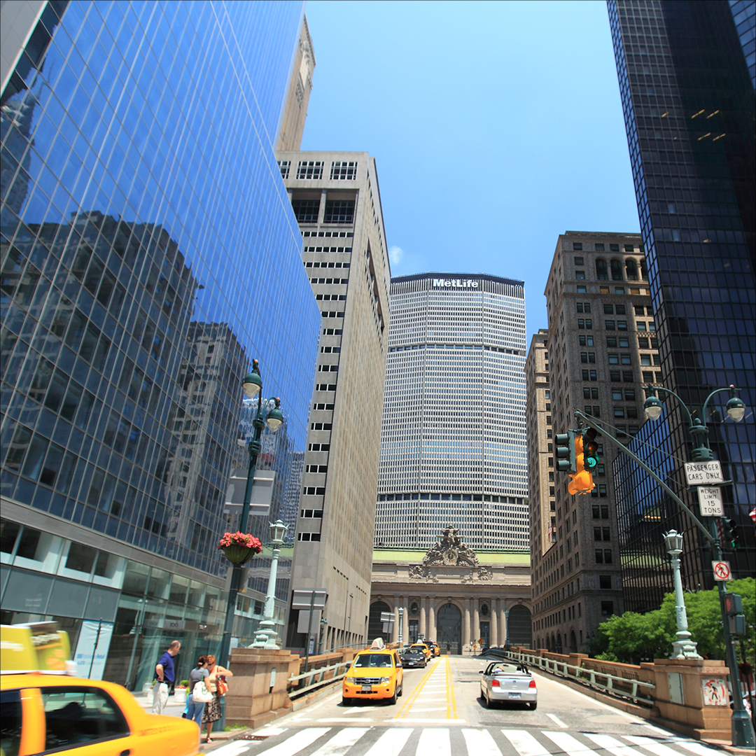 Busy New York City street scene with the MetLife Building, Grand Central Terminal, yellow taxis, and pedestrians crossing at a crosswalk