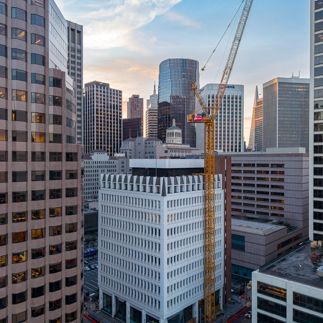 Construction crane rises above downtown high-rise office towers at dusk in a city skyline