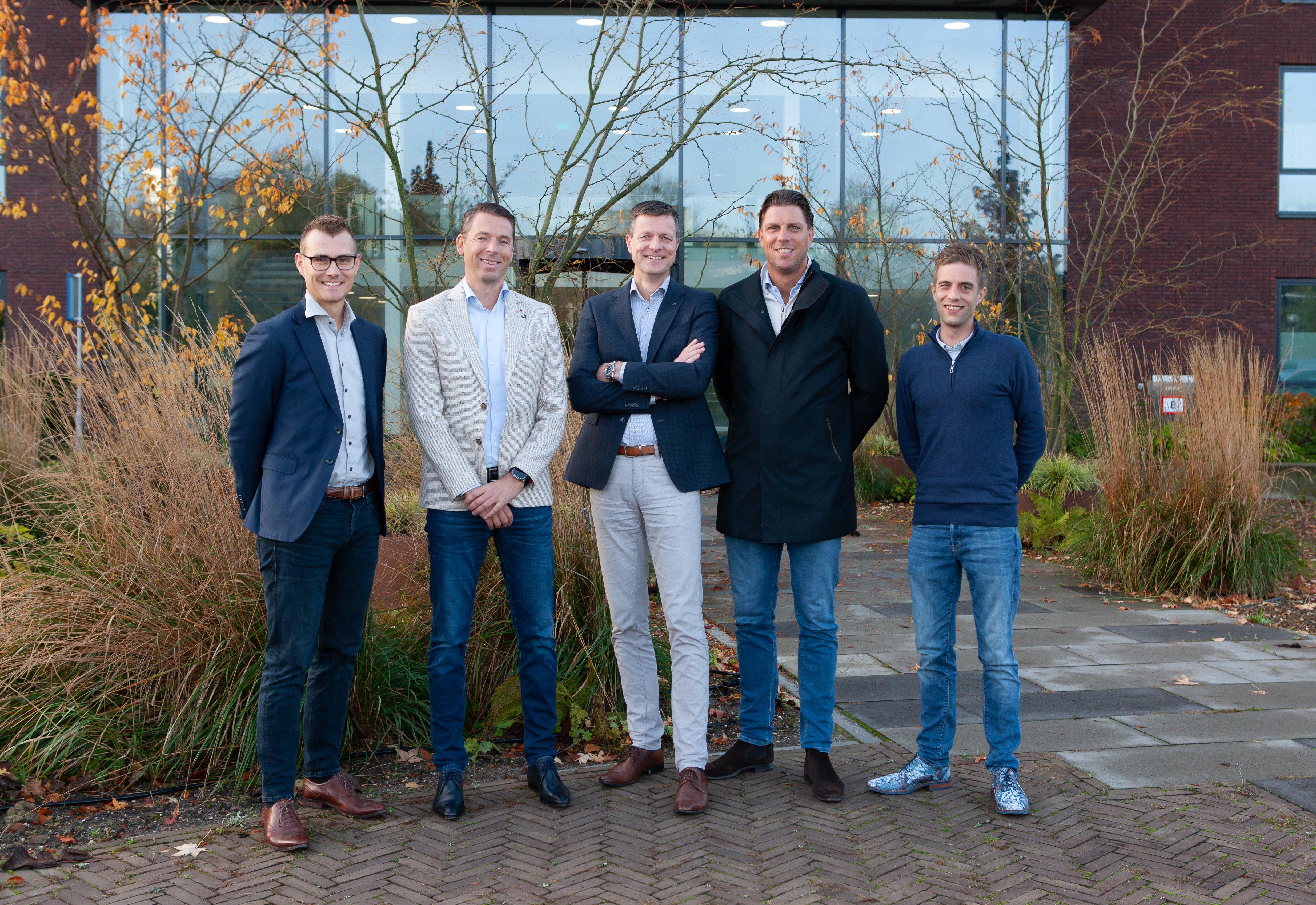 Medewerkers van Caseware Nederland BV die samen met een medewerker op de foto staan voor het nieuwe pand in Apeldoorn.
