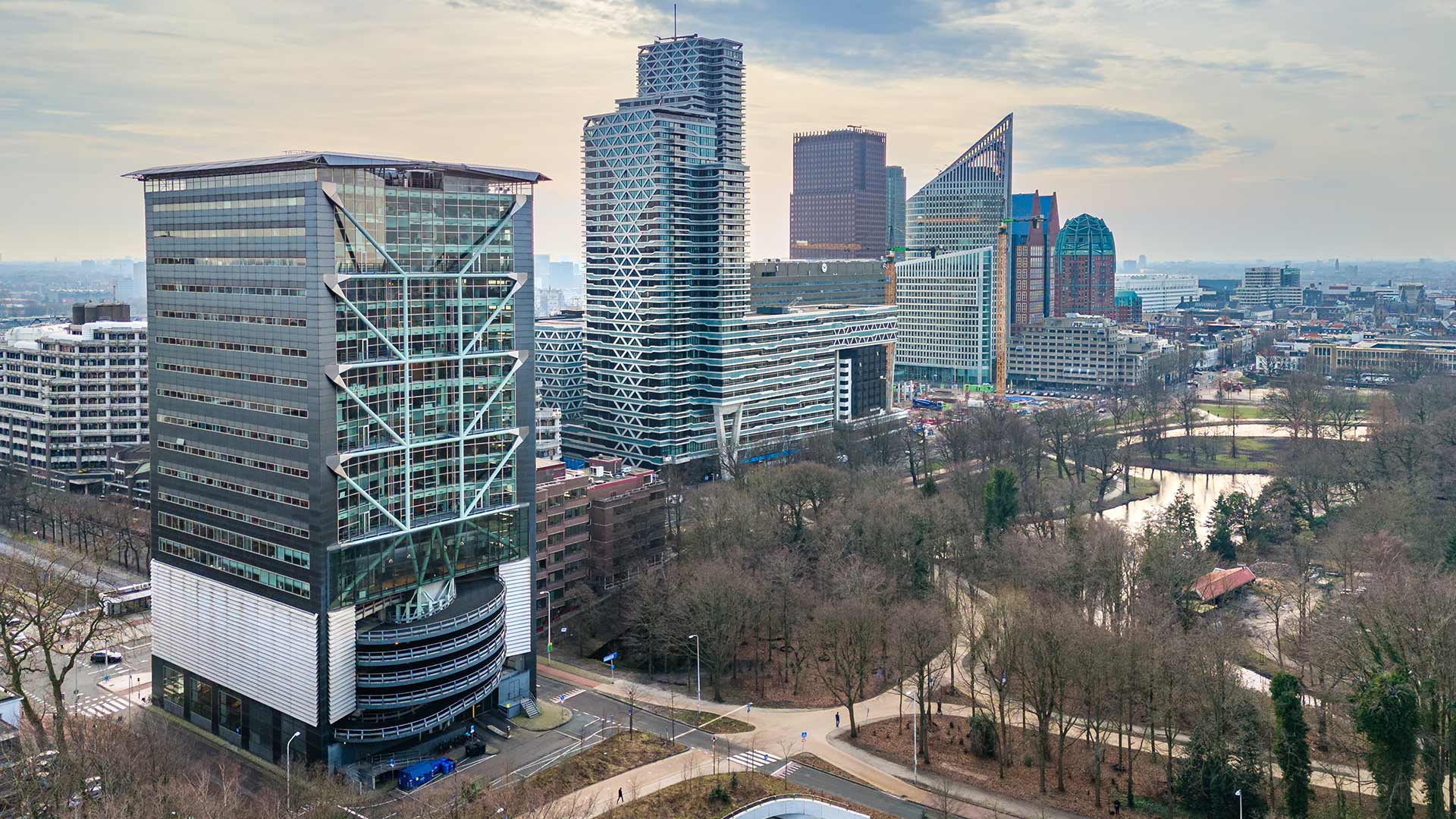 Luchtfoto van Den Haag met de Malietoren links, skyline van het Beatrixkwartier, kruispunt en tunnel, omgeven door Haagse Bos en stedelijke bebouwing.