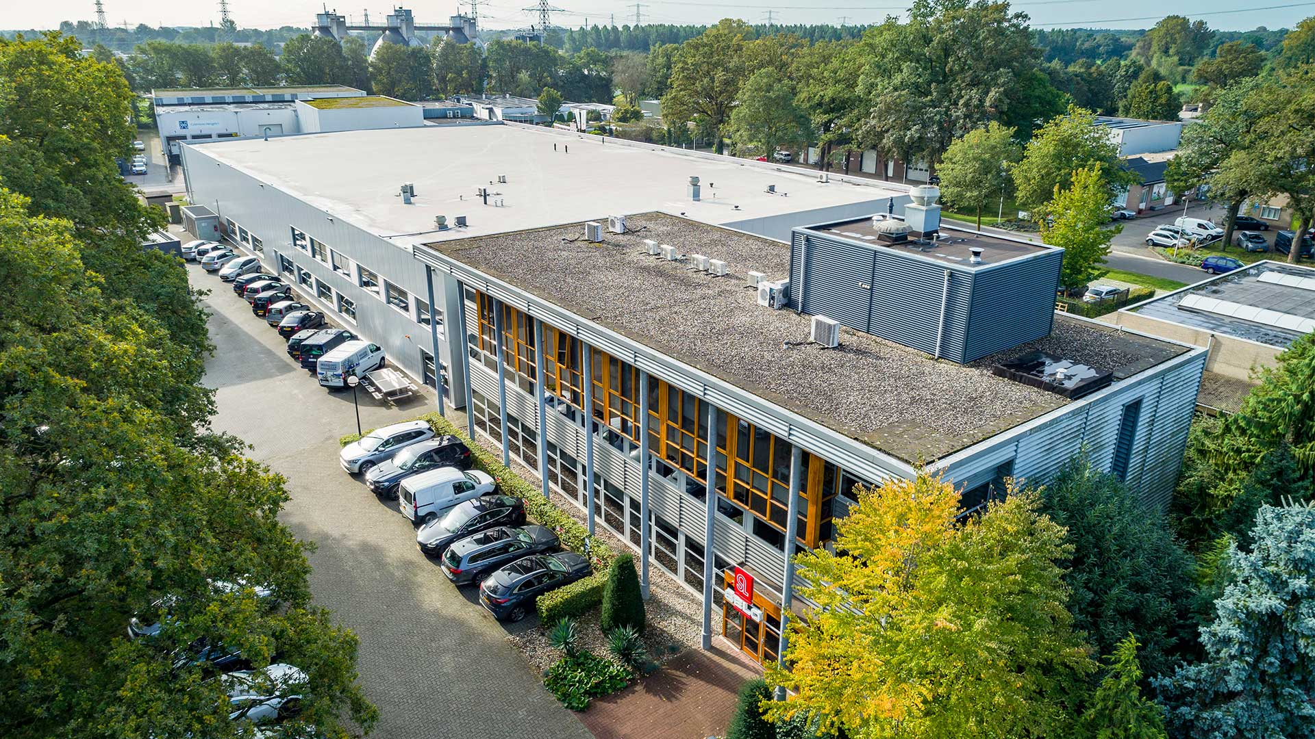Een gebouw in een stedelijk landschap met meerdere verdiepingen op een straathoek. Het gebouw heeft een lichtbruine gevel met grote ramen op elke verdieping. Er zijn geen mensen zichtbaar in de afbeelding.