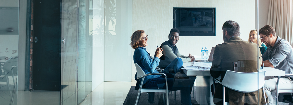 Group of diverse business professionals having a meeting in a modern office, collaborating around a table with documents. Likely discussing commercial real estate deals.