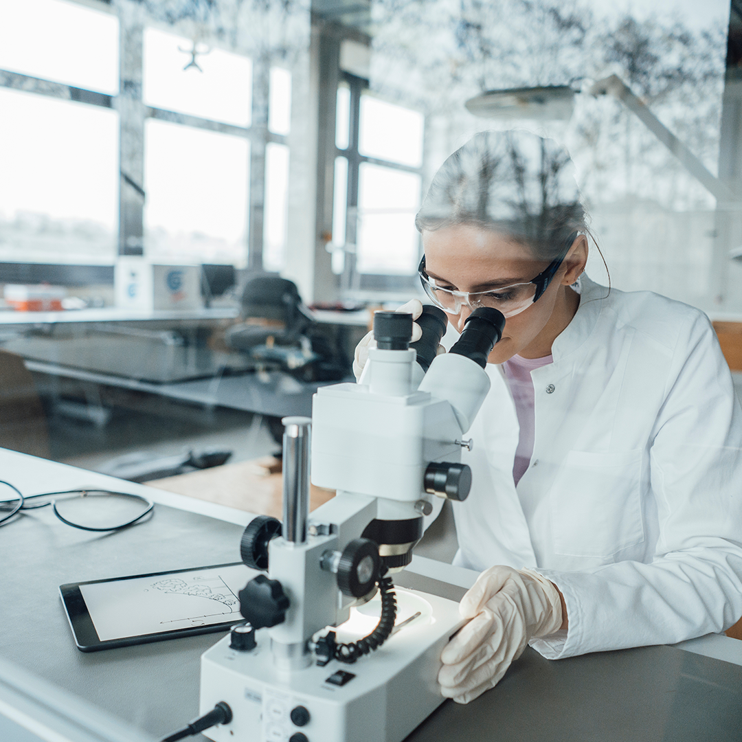 Close-up of a scientist looking through a microscope, conducting laboratory research.