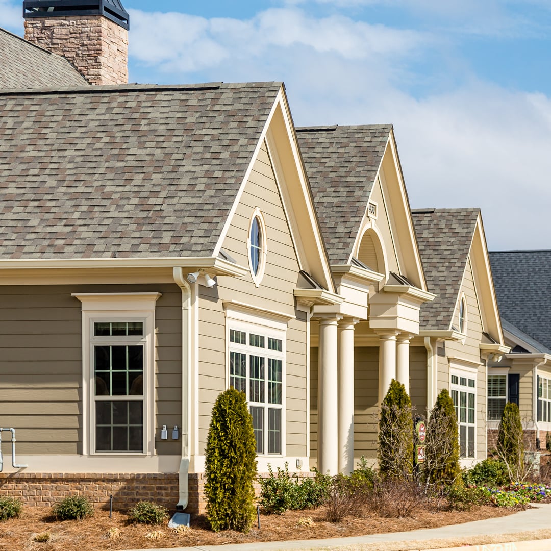 Traditional residential building with pitched roof, decorative gables, and well-maintained shrubs.