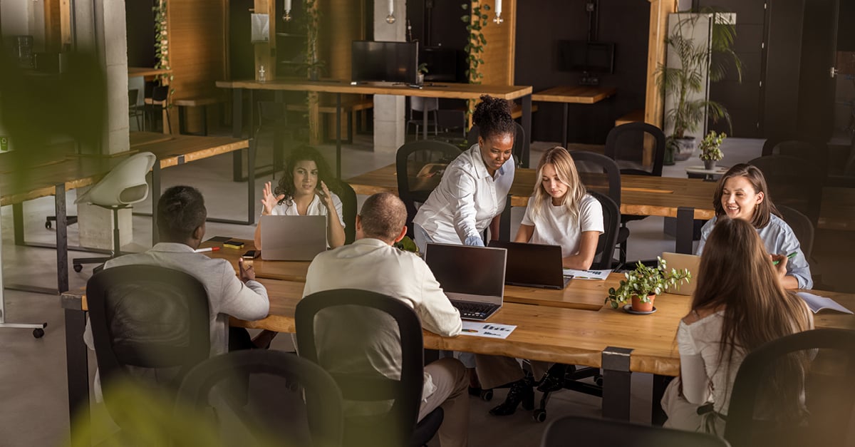 Team collaborating in an open office environment, working together around a large shared table