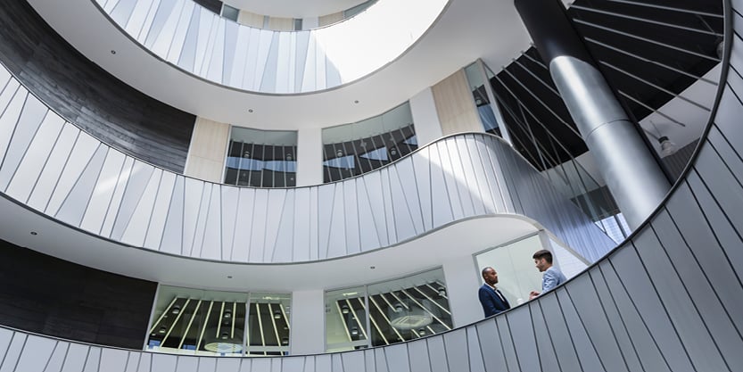 Interior view of a modern multi‑story atrium with curved walkways and open office design