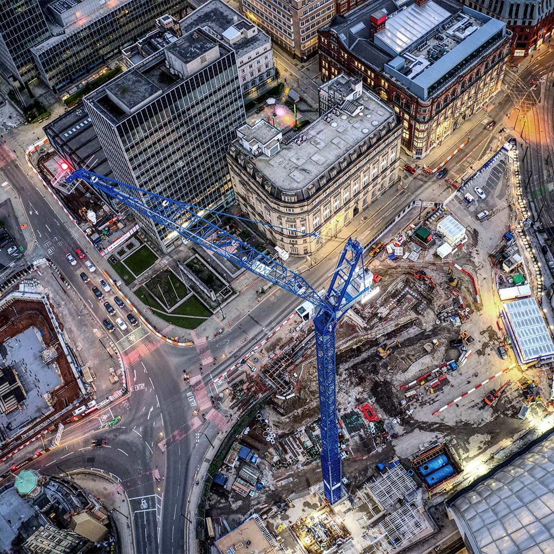 Aerial night view of a blue construction crane over a Manchester city centre building site