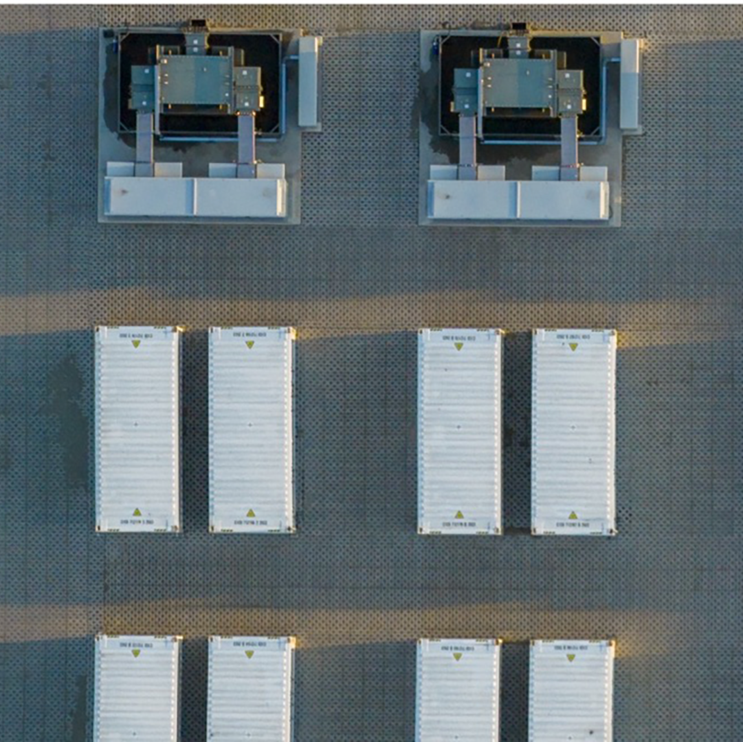 Aerial view of an industrial building rooftop featuring HVAC equipment and rows of energy storage or utility units.