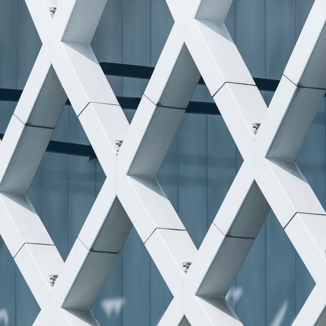 Close‑up view of a modern architectural facade featuring an interlocking geometric lattice pattern against a smooth vertical backdrop