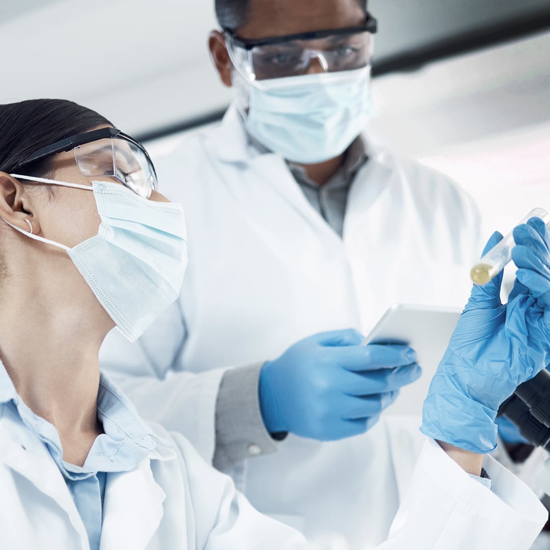 Researchers in a modern laboratory environment examining a sample and reviewing data using scientific equipment and digital devices.