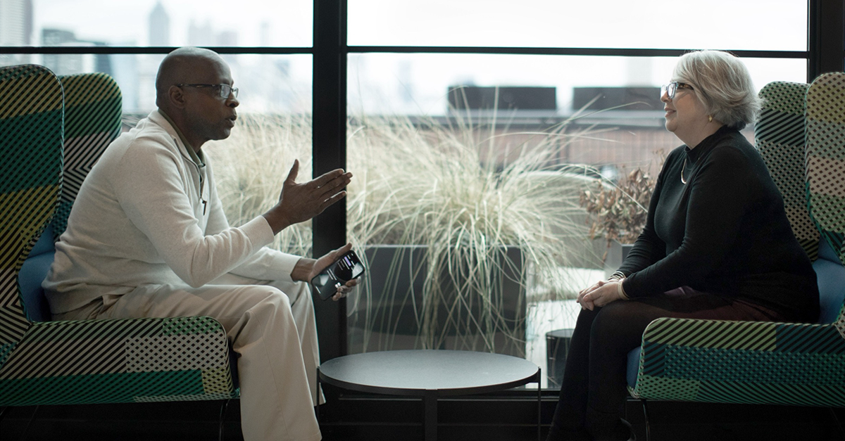 Image shows a professional business meeting between a man and woman discussing commercial real estate. A tablet is visible.