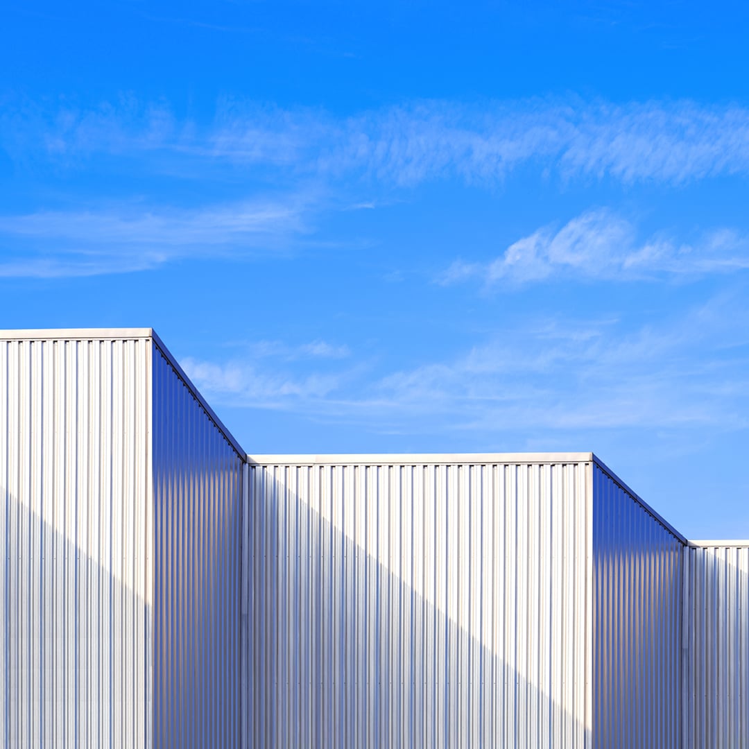 Close view of a modern industrial building with white corrugated metal walls forming clean geometric lines