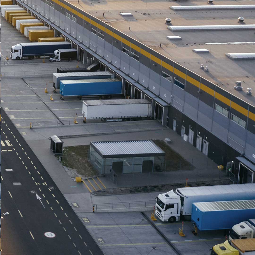 Aerial view of a large warehouse surrounded by parked trucks, showcasing logistics and distribution operations.