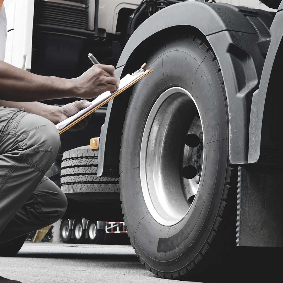 Person writing on a clipboard next to a 18-wheeler truck.