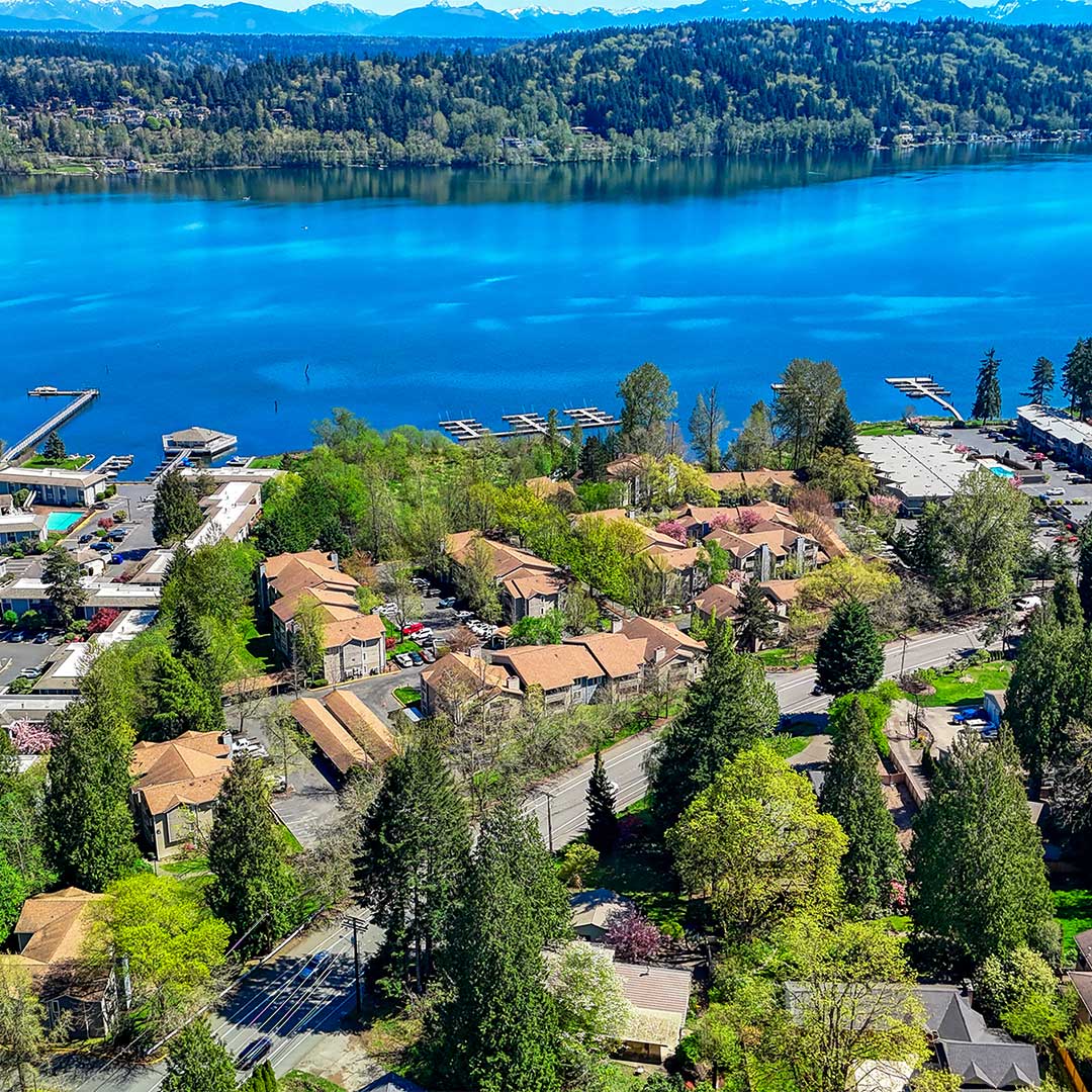 Aerial of apartment building with orange roofs, next to a lake.