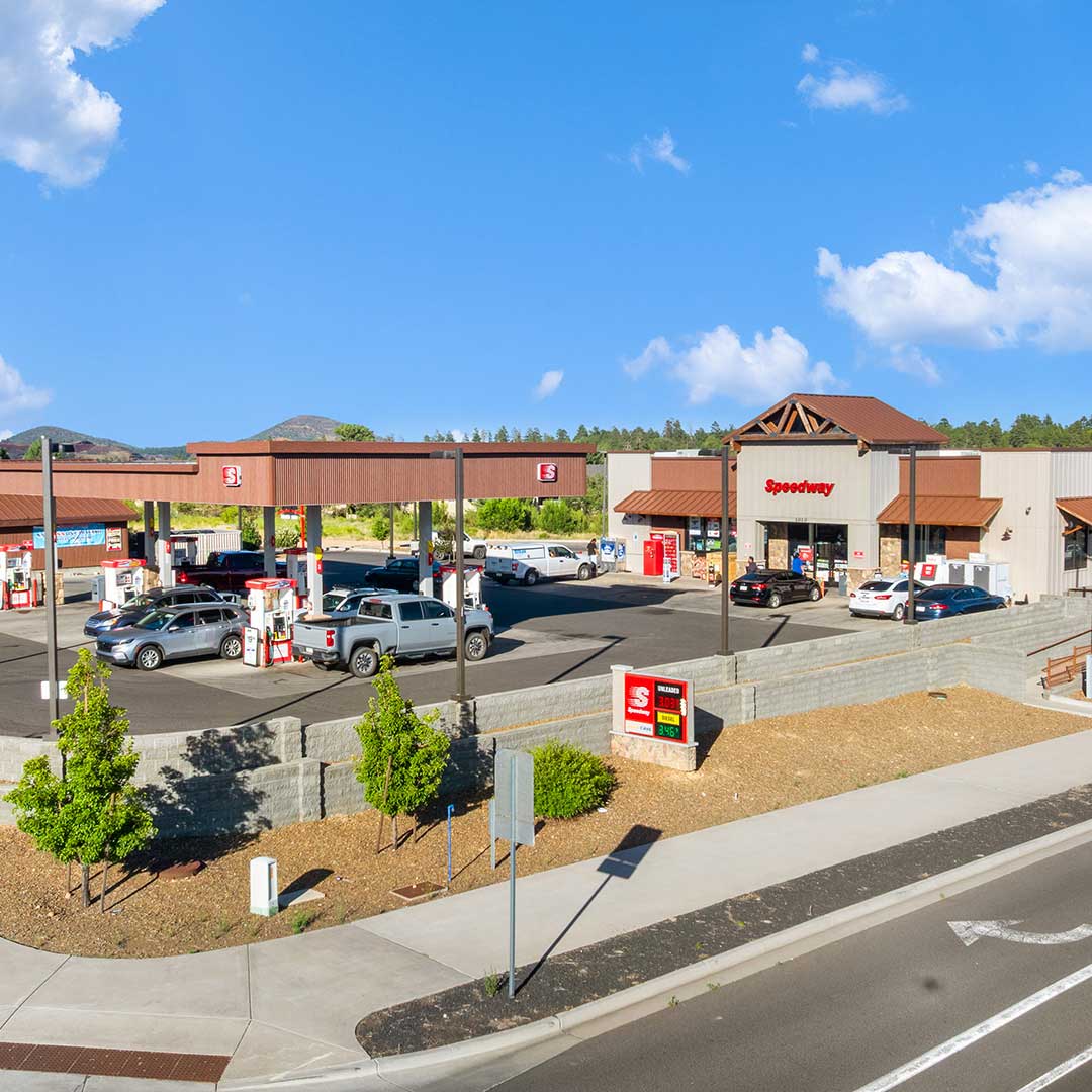 Speedway gas station with multiple fuel pumps and cars, located in a sunny area with blue skies.