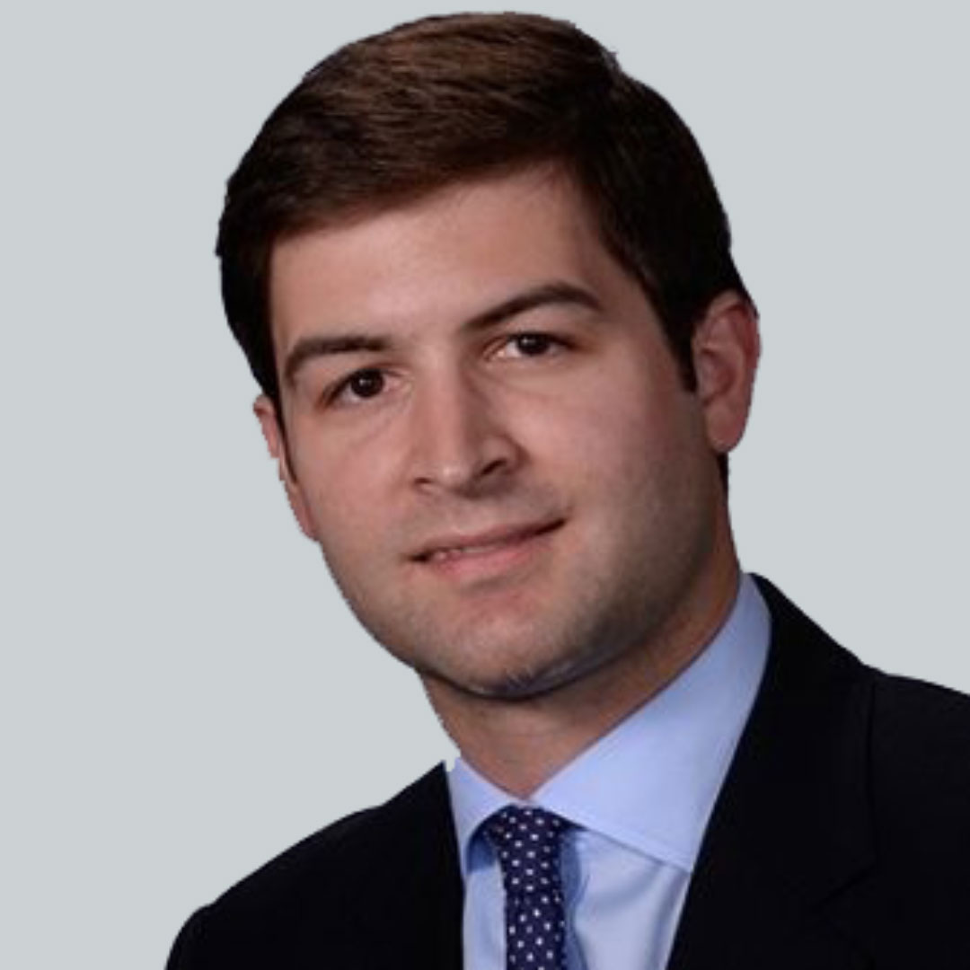 Headshot of William Wilkins in a suite with a blue tie and gray background.