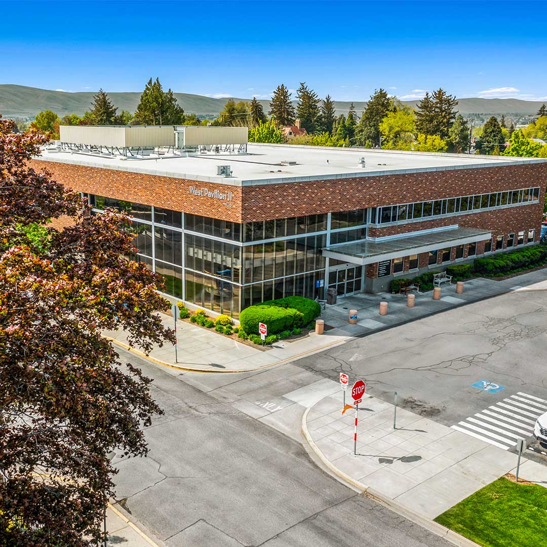 Medical outpatient building in washington with red brick outside. trees and mountains in the background with blue sky.