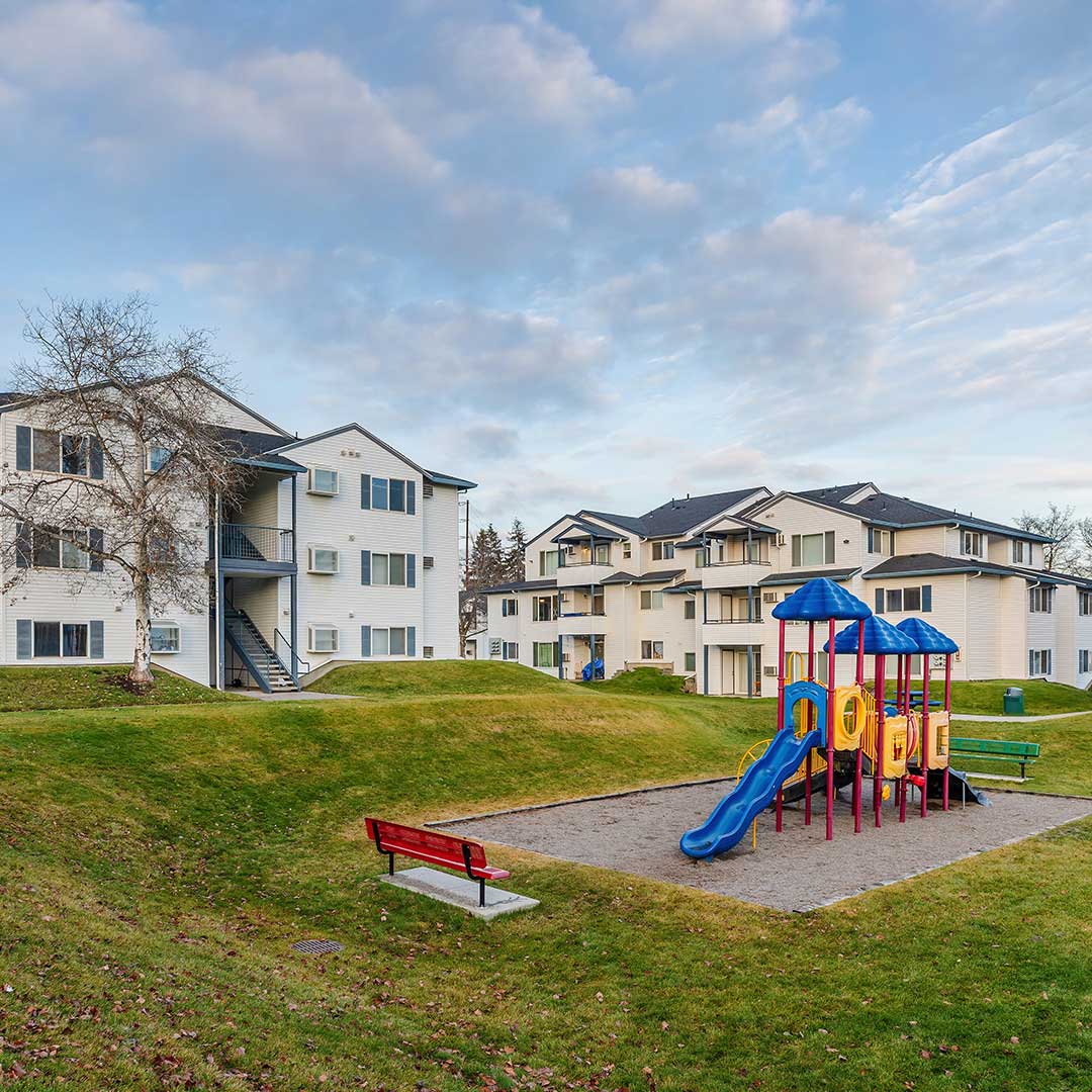 Two three-story apartment buildings, with a blue and yellow playground.