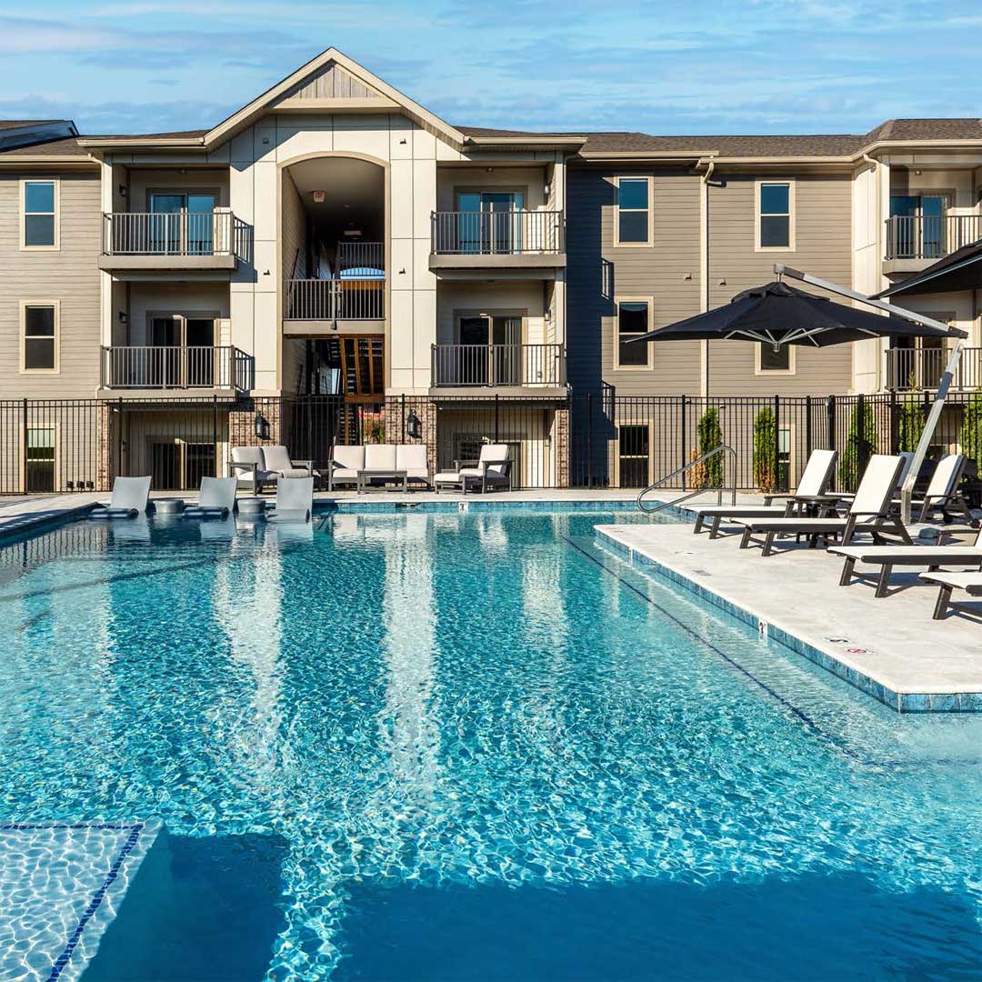 A multifamily property by a pool on a sunny day