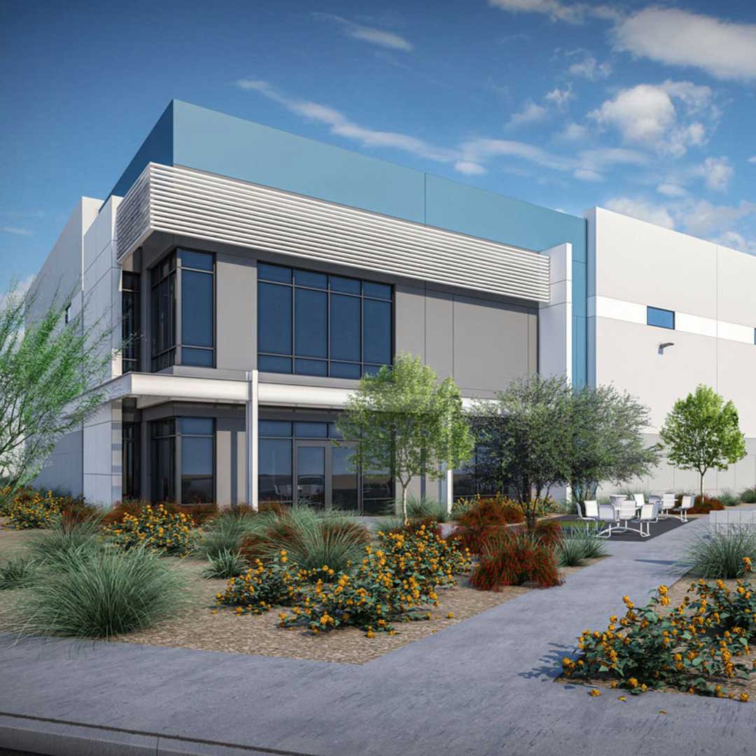 Modern commercial building with large glass windows, white and blue exterior walls, surrounded by landscaped greenery and an outdoor seating area with tables and chairs under a partly cloudy sky.