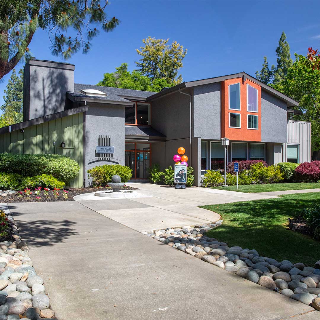 Light grey exterior of clubhouse at Falls at Arden apartment community.