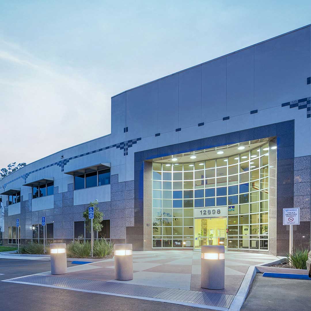 Modern office building with large glass entrance and illuminated walkway.