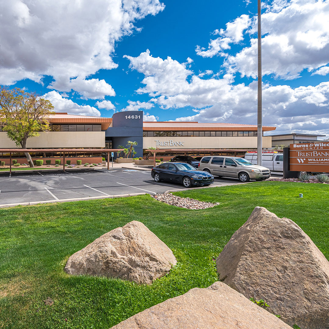 TrustBank building at 14631 N Scottsdale Rd with landscaped lawn and parked cars under a blue sky.
