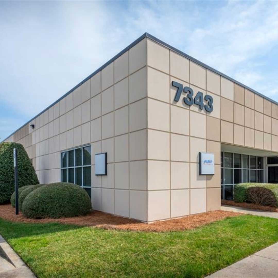 Building at 7343 in West Friendly Business Park with beige grid-pattern exterior and landscaped shrubs.