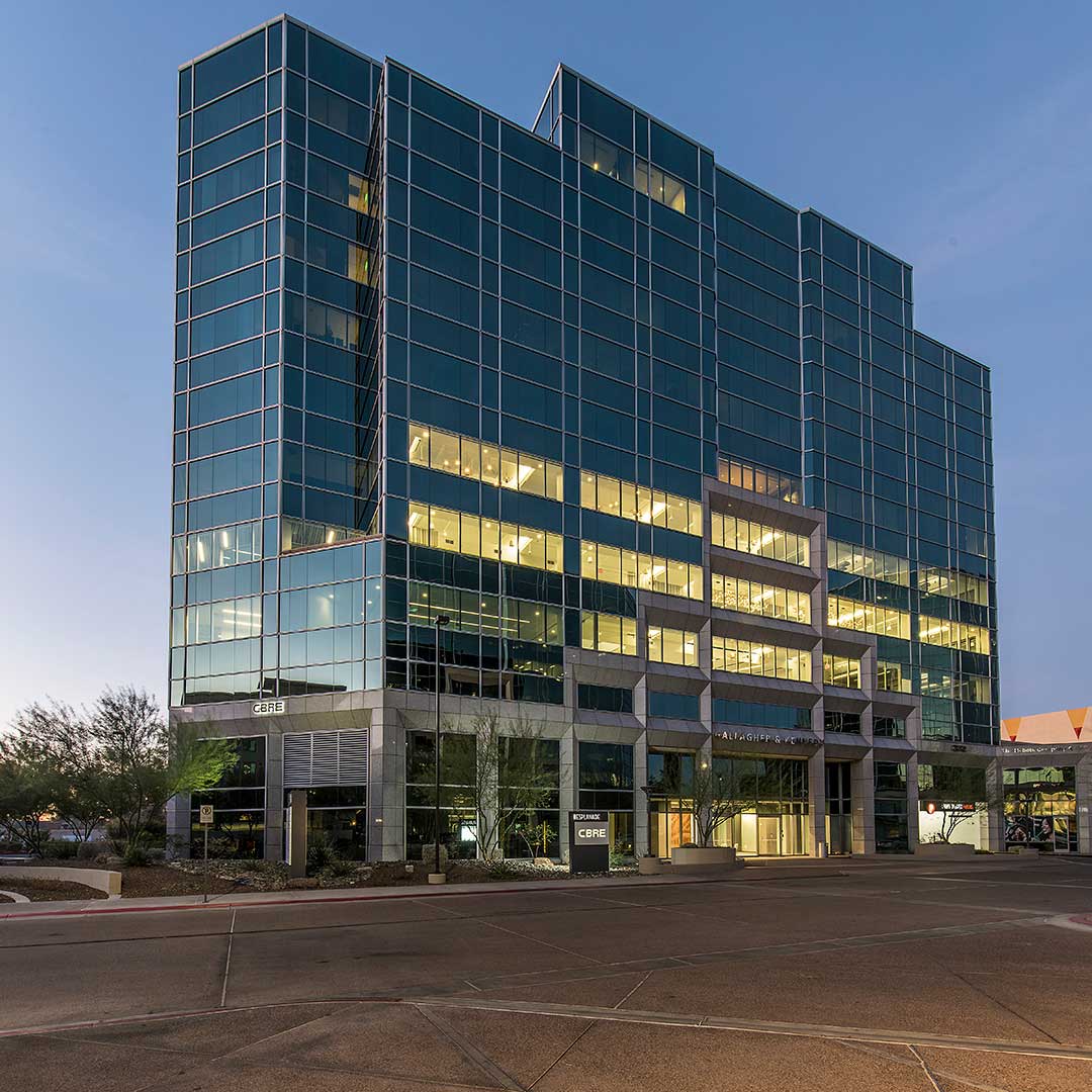 Sleek glass office building with CBRE signage, reflective windows, and landscaped entrance.