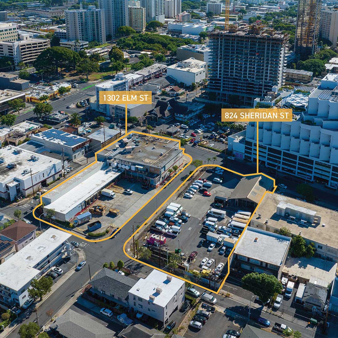 Aerial view of old warehouse and trailer parking on the left and parking lot on the right.
