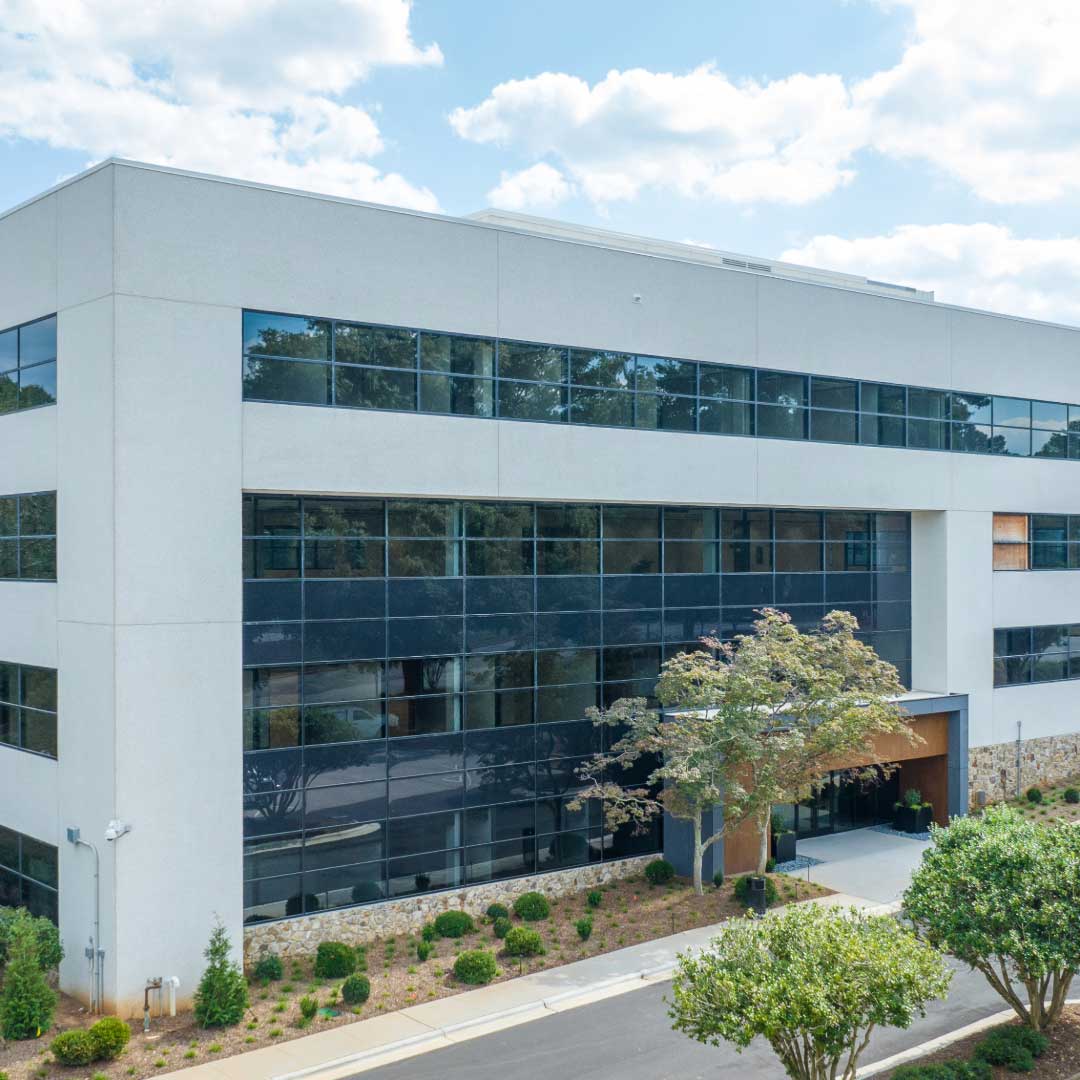 The modern, three-story office building at The Grove, with large windows and a landscaped entrance.