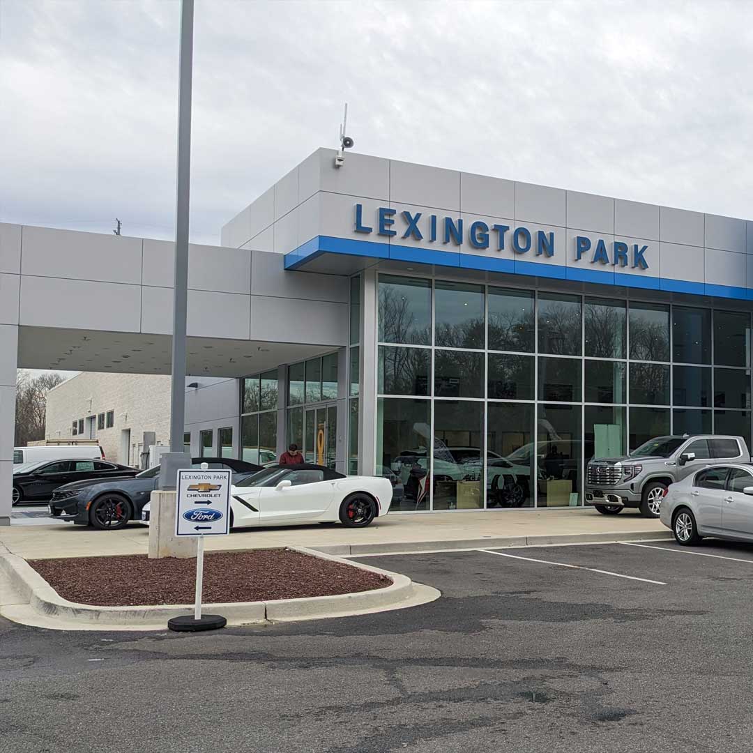 Exterior of Lexington Park Chevrolet Buick GMC dealership featuring modern glass showroom, parked vehicles, and branded signage.