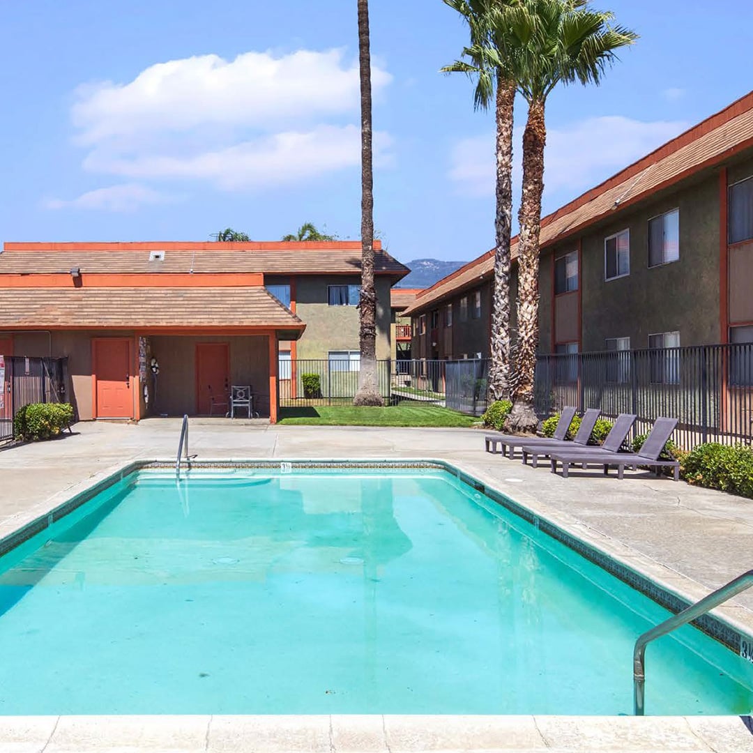 Mountain View Apartments San Bernardino CA outdoor pool with lounge chairs, palm trees, and mountain views