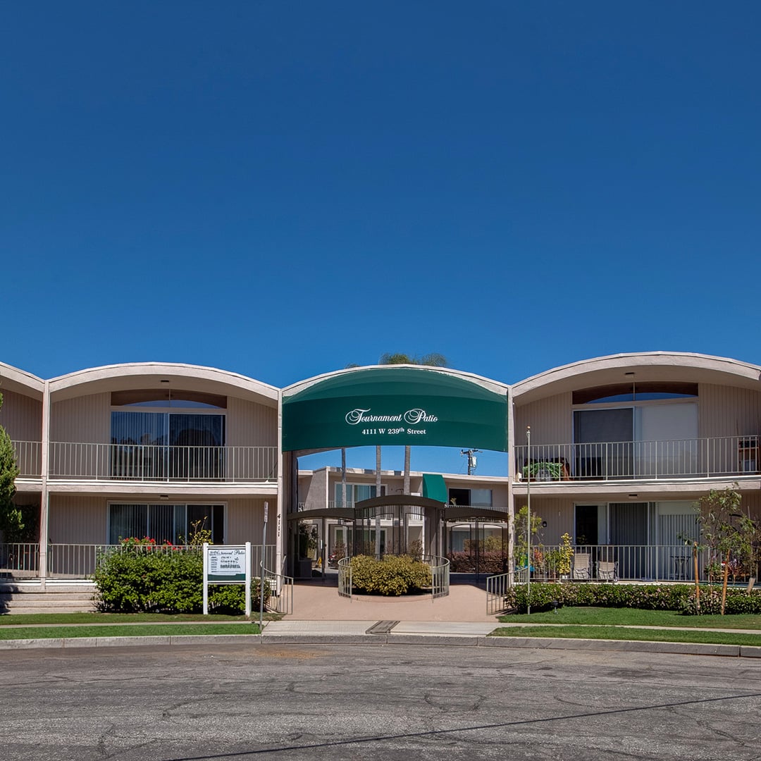 Tournament Patio Apartments exterior at 4111 W 239th St, Torrance CA — mid-century multifamily building with curved rooflines and green entry canopy.