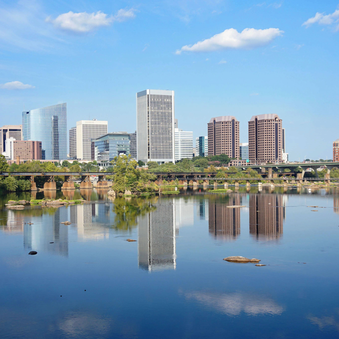 Richmond Virginia downtown skyline reflecting on the James River with modern skyscrapers, bridge, and blue sky