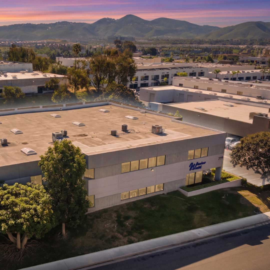 Modern industrial office and warehouse complex in San Marcos, CA with landscaped grounds and mountain backdrop at sunset, ideal for commercial real estate and logistics.