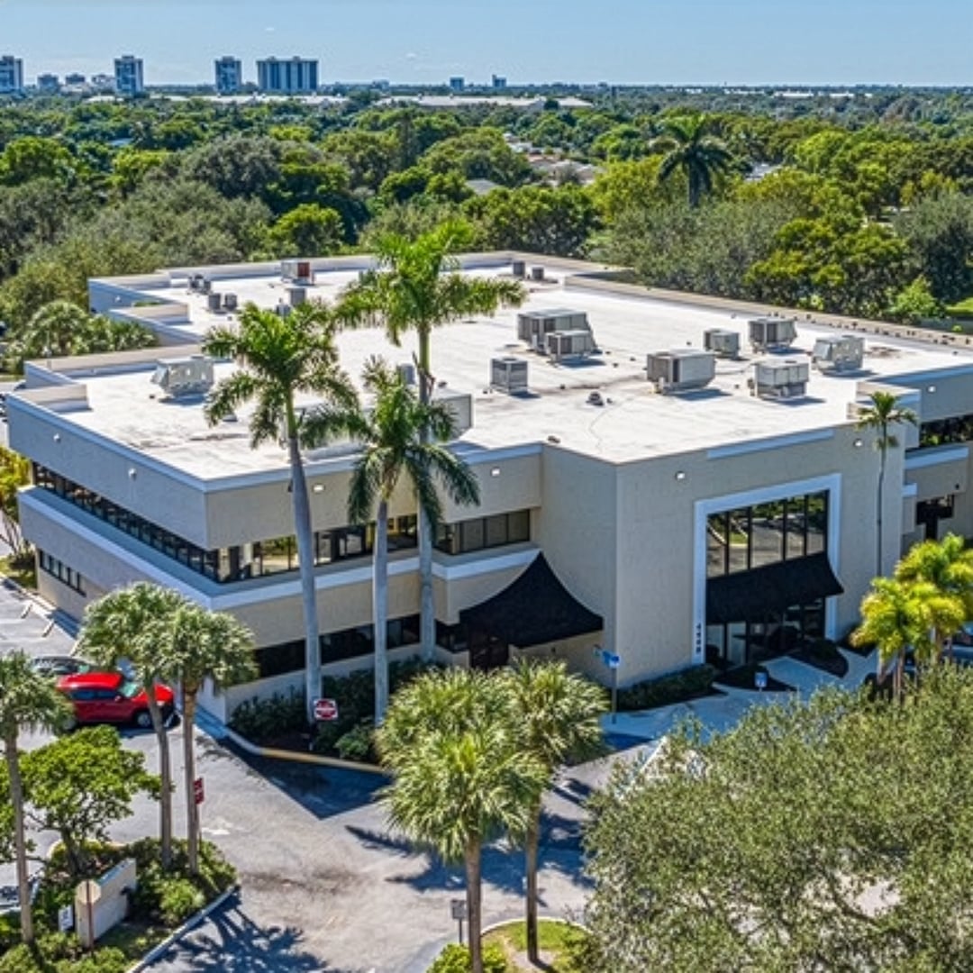 Aerial view of a modern medical office building surrounded by palm trees in West Palm Beach, Florida.
