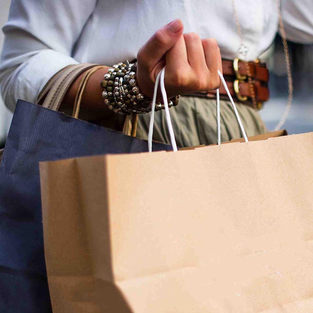 Person carrying multiple shopping bags, illustrating consumer activity tied to Tucson’s retail market and big-box absorption trends in CBRE’s 2025 report.