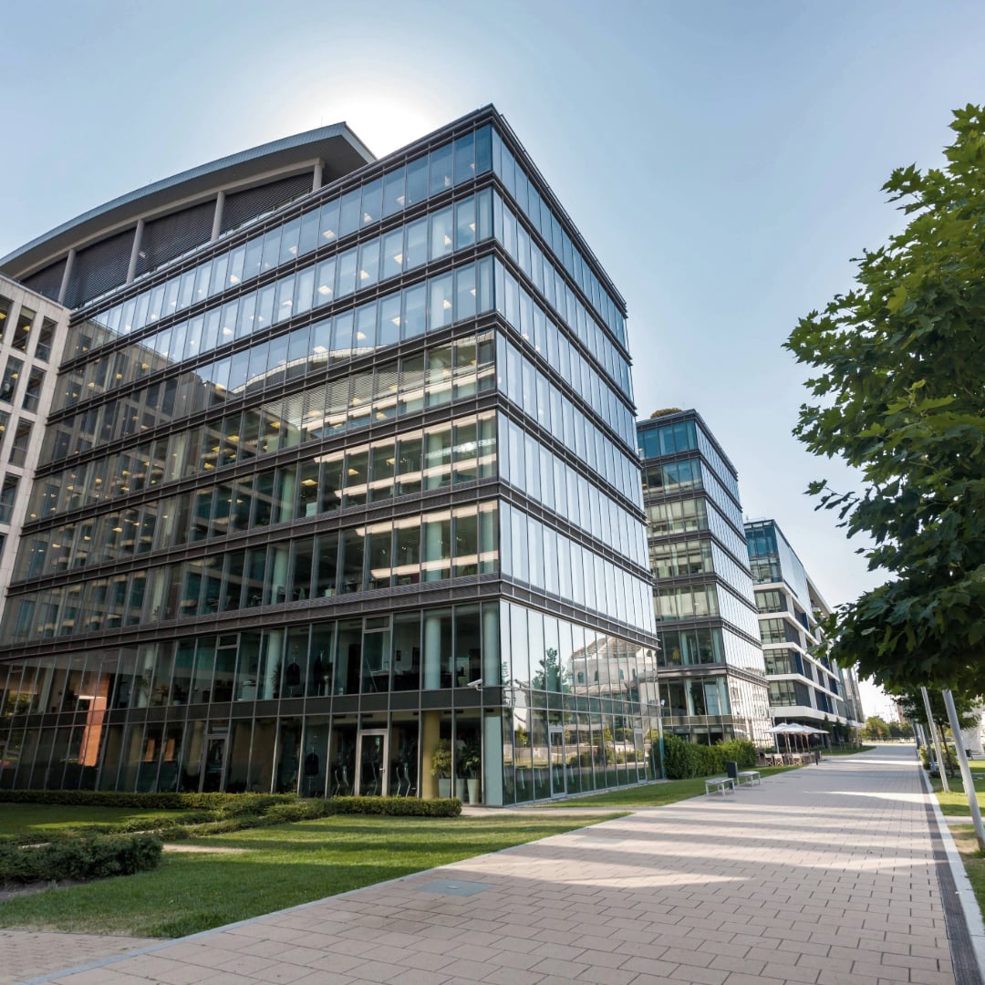 Modern glass office buildings in a landscaped business district, representing Class A commercial real estate and contemporary workplace design