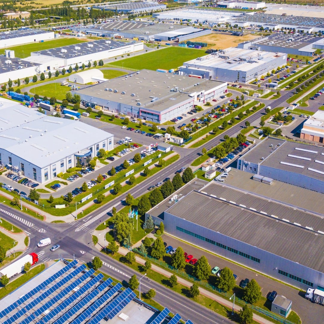Aerial view of a modern industrial logistics park with warehouse buildings, distribution centers, roadways, parking areas, and solar panels.