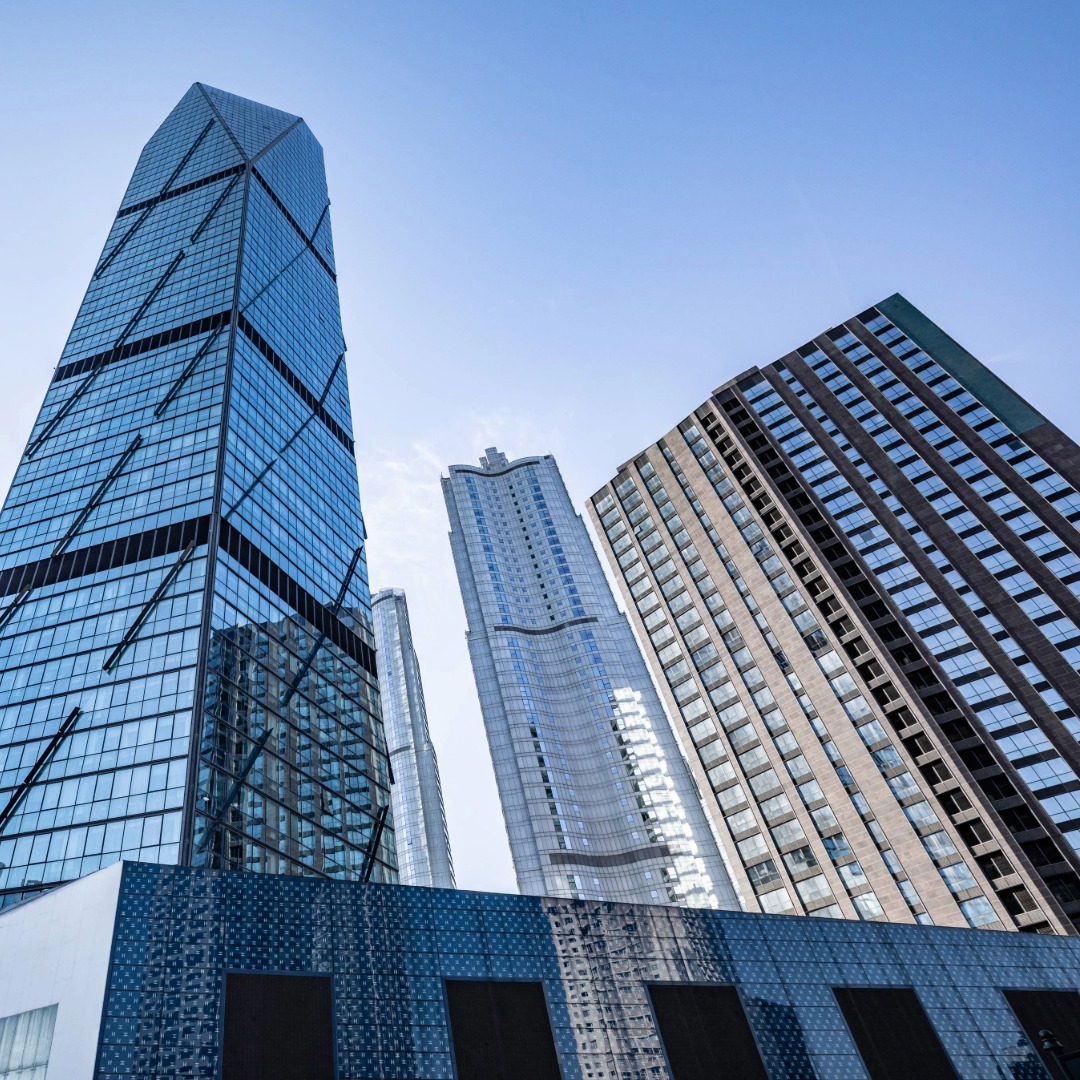 Low-angle view of modern glass skyscrapers against a clear blue sky in an urban cityscape.