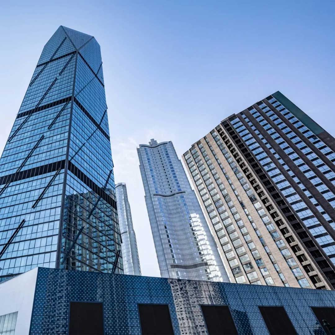 Low-angle view of modern commercial skyscrapers with glass facades in a city skyline.