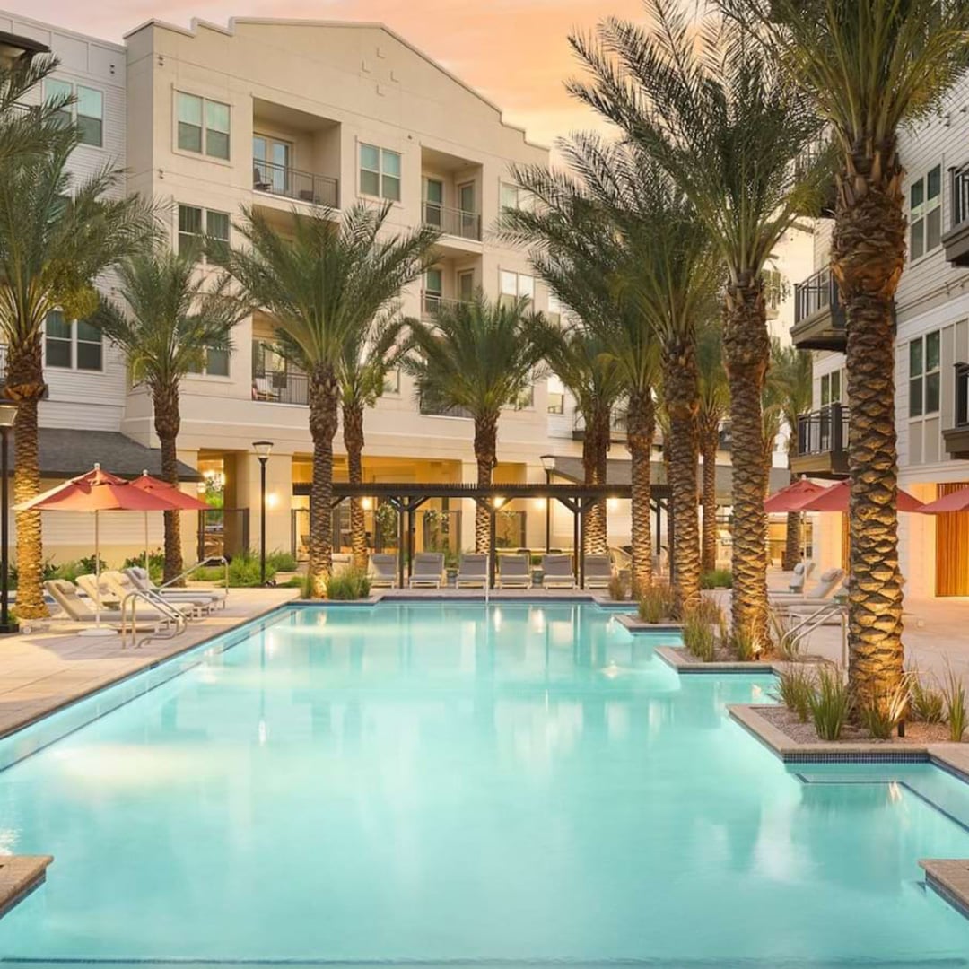 Resort-style swimming pool with palm trees and lounge chairs at The Tyler multifamily community in Gilbert, Arizona, arranged by CBRE