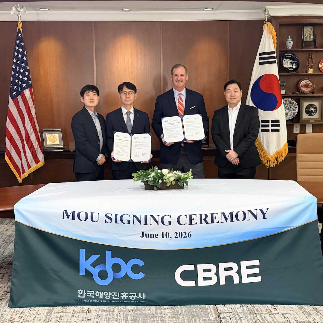 Four individuals standing behind a table holding signed documents