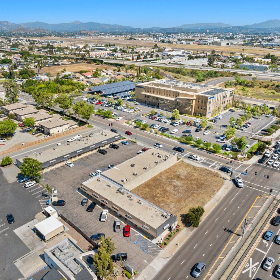 Aerial view of retail commercial properties at 8781 Cuyamaca Street and 9822 Buena Vista Avenue in Santee, CA with surface parking and mountain backdrop.