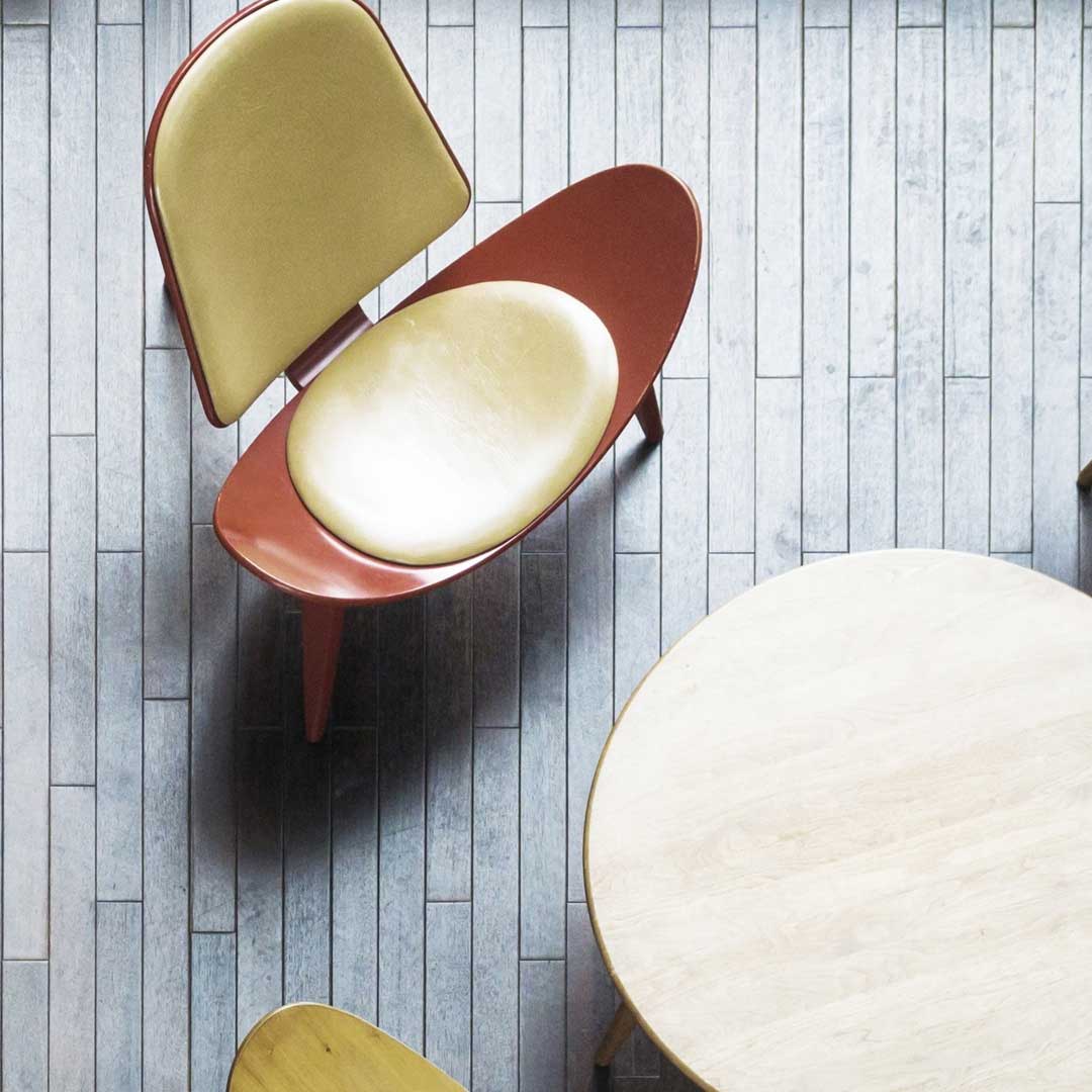 A stylish, mid-century modern chair with a curved wooden frame and light-colored cushioned seat/back.