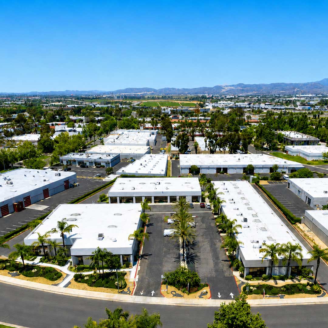 Drone photo of Alcalde Business Center industrial park in Laguna Niguel CA with paved parking lots, landscaped grounds, and Southern California mountain views