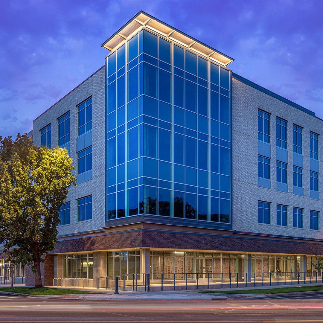 Exterior view of a modern medical office building with a glass corner façade and brick exterior photographed at dusk.